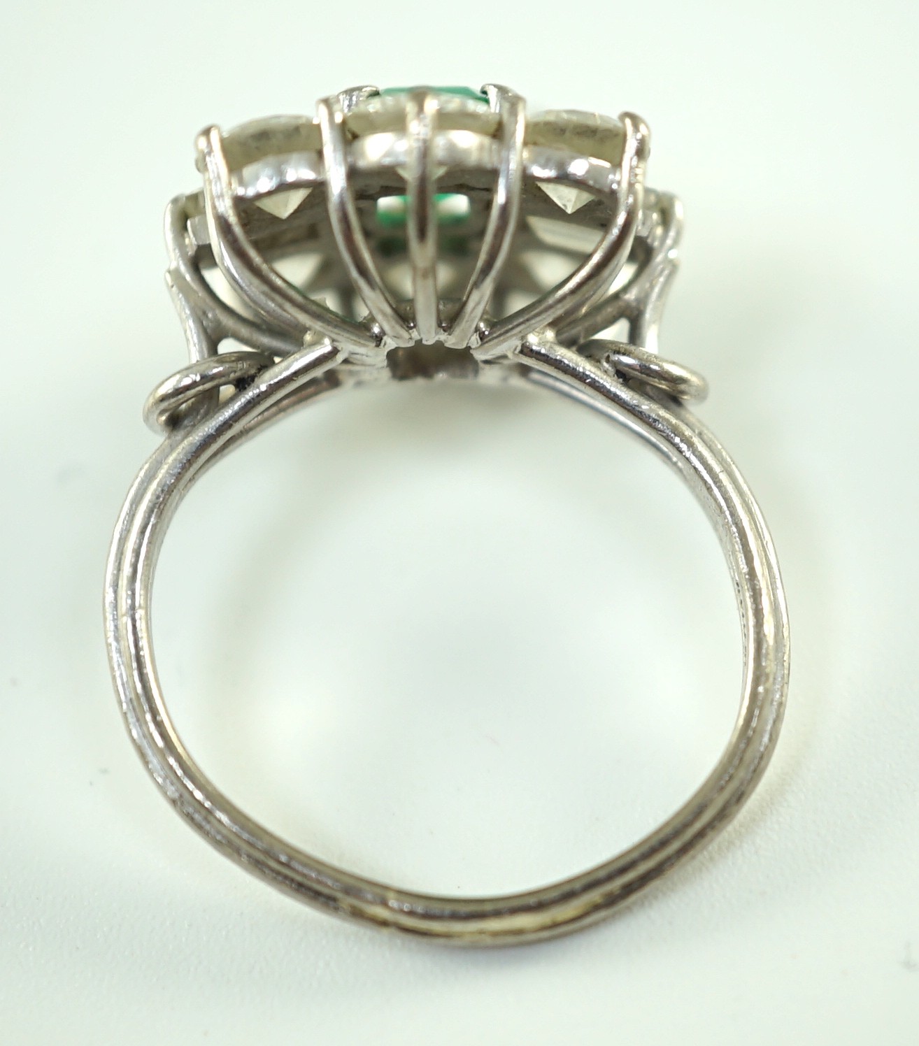 A mid 20th century 18kt white gold, single stone emerald and round and baguette cut diamond cluster ring